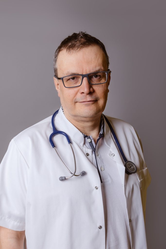Kierownik Oddziału Alergologiczno-Rehabilitacyjnego dr n. med. Marek Mikołajczyk, Mężczyzna w okularach, w białym kitlu na szarym tle