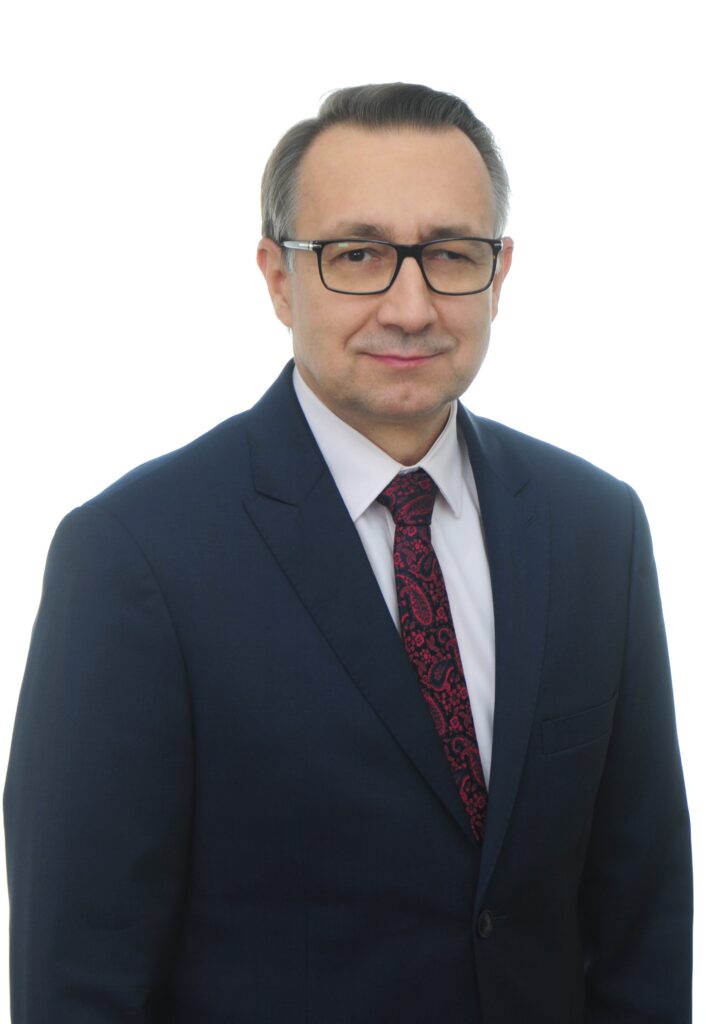 Dyrektor Szpitala dr hab. inż. Roman Lewandowski, prof. UWM. Mężczyzna w okularach, ubrany w ciemno niebieski garnitur, granatowy krawat, ustawiony na białym tle. 